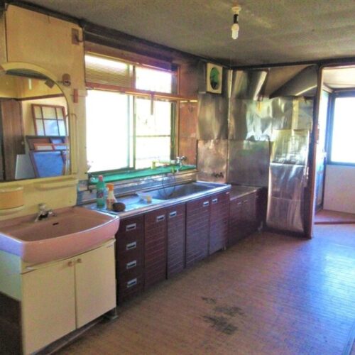 岩手県遠野市の物件の台所。キッチンの隣に洗面台があるレイアウト。ダイニングキッチンは、天井や壁の状態がよくないので要改修。