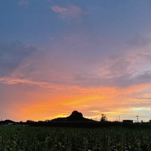 島のシンボル城山に夕日が沈む（沖縄県伊江村）