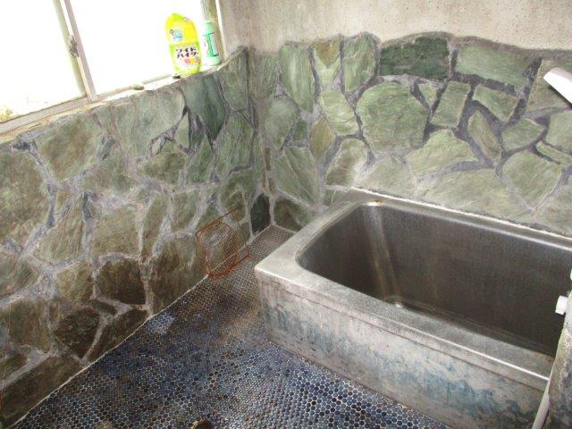鹿児島県鹿屋市の物件の浴室。石壁やタイルの床がまるで温泉のような浴室で、シャワー付きです。