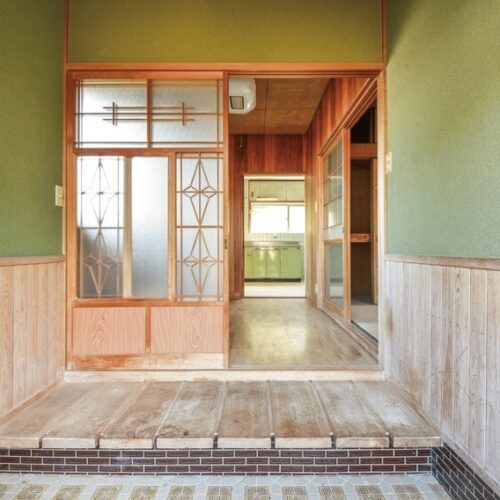 愛媛県宇和島市の物件のガラス戸などがレトロな趣の玄関。その奥にホールを兼ねた洋室がある。