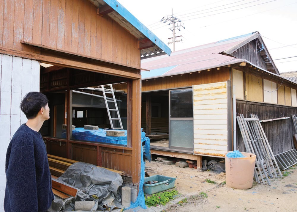 ミカンの保管倉庫と築約100年の母屋を、コンクリートで増築した台所・風呂・トイレ棟がコの字形につないでいる／愛媛県松山市中島