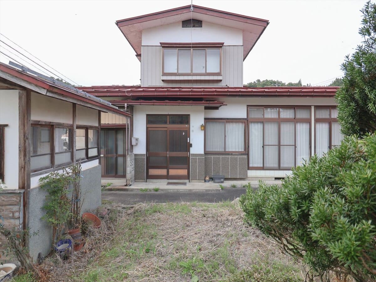 山形県大江町の物件の外観。敷地の中に大きめの小屋1棟、道路を挟んで二階建て車庫1棟付き。