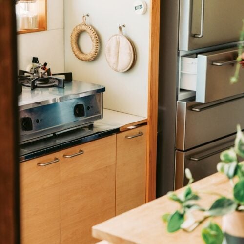 キッチン下収納は、⼀般的な公団型流し台の扉をDIYでシナ材に変更。無印良品の冷蔵庫の取っ⼿形状に合わせて収納扉の取っ⼿も付け替え、デザインに統⼀感を持たせている／島のおばあちゃんちで暮らす