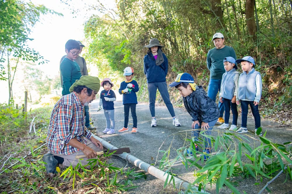 器用に竹を切り分けていく章二さんに興味津々の子どもたち。このあとノコギリを使って親子で挑戦した/大分県豊後高田市