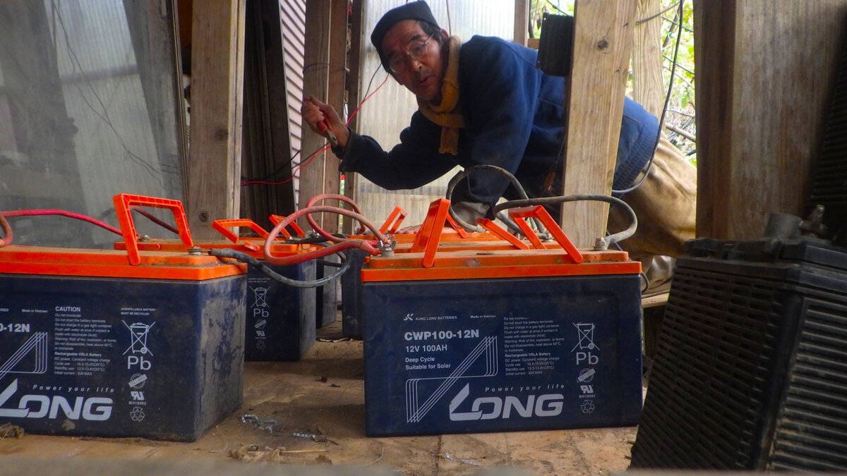自宅の太陽光発電用バッテリーを点検・接続する自給的な田舎暮らしのエネルギー管理